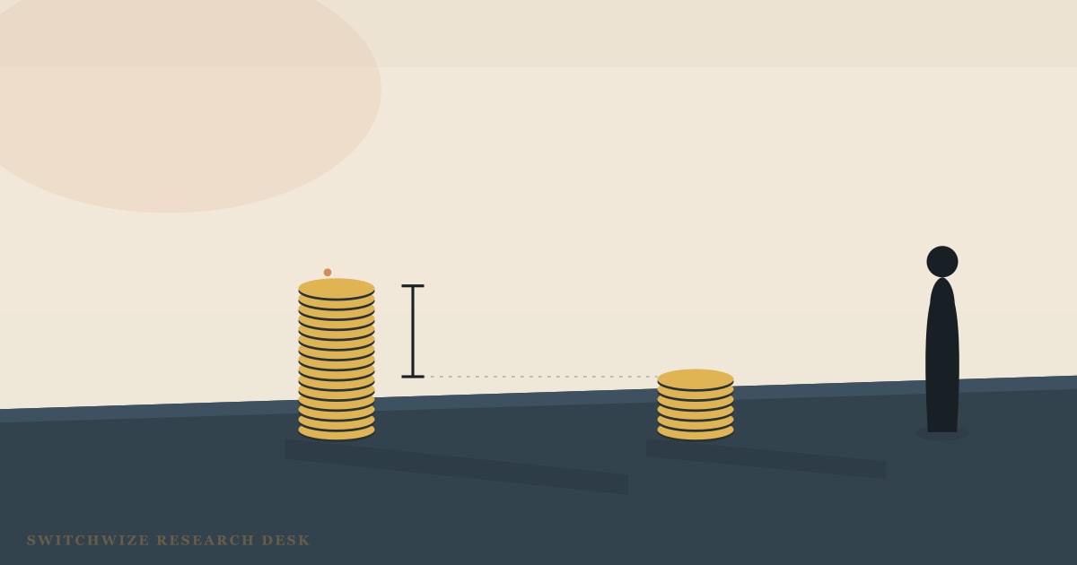 Two stacks of gold coins on a slate desk, one tall and one far shorter, with a measuring bracket marking the gap between their heights and a single warm light overhead.